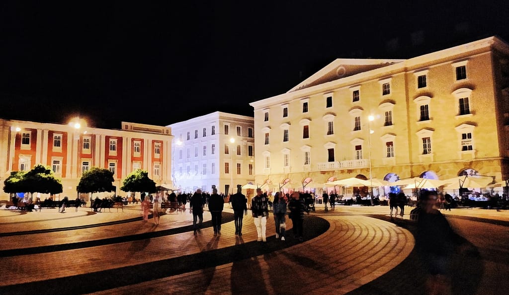 Street lamps and lit façades in central Timișoara after dark.